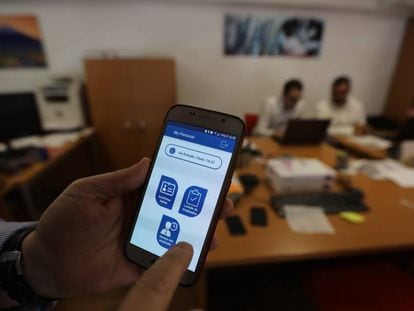 Un usuario muestra una aplicación móvil para fichar en el puesto de trabajo.