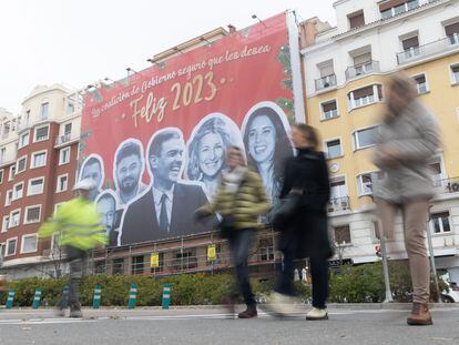 Tres mujeres caminan frente a la lona que han colgado las juventudes del PP en las inmediaciones de la sede del Partido Socialista, este jueves, en Madrid.