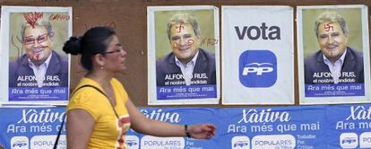 Una vecina pasa por delante de los carteles electorales de Alfonso Rus colocados en la noche del jueves en Xàtiva.