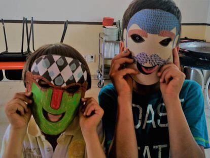 Dos niños acogidos en la parroquia de San Carlos Borromeo en Madrid posan con máscaras. 