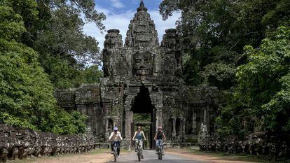 Un grupo de turistas recorre el enorme complejo de Angkor en bicicleta.