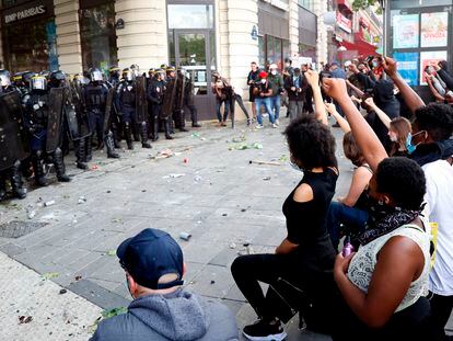 Manifestantes contra la violencia policial en París levantan el puño con la rodilla doblada ante los agentes que vigilaban la protesta