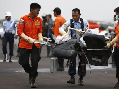 Miembros del equipo de rescate indonesio llevan restos del avión de Air Asia recuperados este lunes en el mar de Java. 