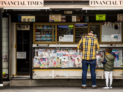 Un padre, con su hijo, en un kiosco de prensa en las inmediaciones del hospital de La Paz de Madrid.