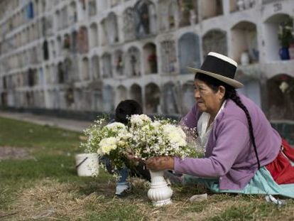 Una mujer adorna con flores la tumba de un familiar.