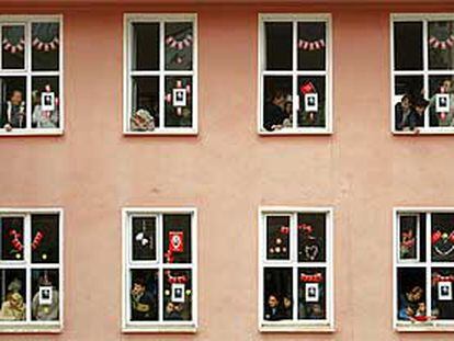 Varias personas se asoman a las ventanas de un colegio electoral para ver cómo abandona el edificio Erdogán, el líder del Partido de la Justicia y el Desarrollo.