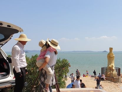 Una mujer mira por un catalejo las islas taiwanesas de Kinmen desde la playa en Xiamen (China)