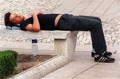 Un joven descansa del ajetreo de las fiestas de Bilbao sobre un banco de piedra de la plaza Moyúa, como si de un colchón de plumas se tratara.