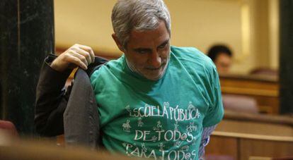 El diputado de IU, Gaspar Llamazares, se quita la chaqueta sobre la camiseta verde con el lema &quot;Escuela p&uacute;blica de todos para todos&quot;.