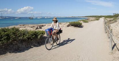 Una mujer circula en bicicleta por la isla balear de Formentera.