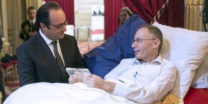 Hollande entrega un galardón a Claude Emmanuel Triomphe, uno de los heridos del 13-N, el 22 de diciembre en el Elíseo.