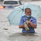 This photo taken on July 20, 2021 shows a man wading through flood waters along a street following heavy rains in Zhengzhou in China's central Henan province. (Photo by STR / AFP) / China OUT