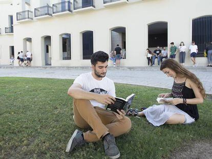 Dos estudiantes leen en uno de los jardines de la Facultad de Derecho de la Universidad de Sevilla.