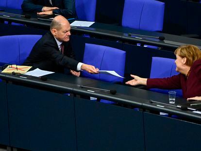 El ministro de Finanzas alemán, el socialdemócrata Olaf Scholz, entrega un documento a la canciller alemana, la conservadora Angela Merkel, en una sesión en el Bundestag, el pasado jueves en Berlín.