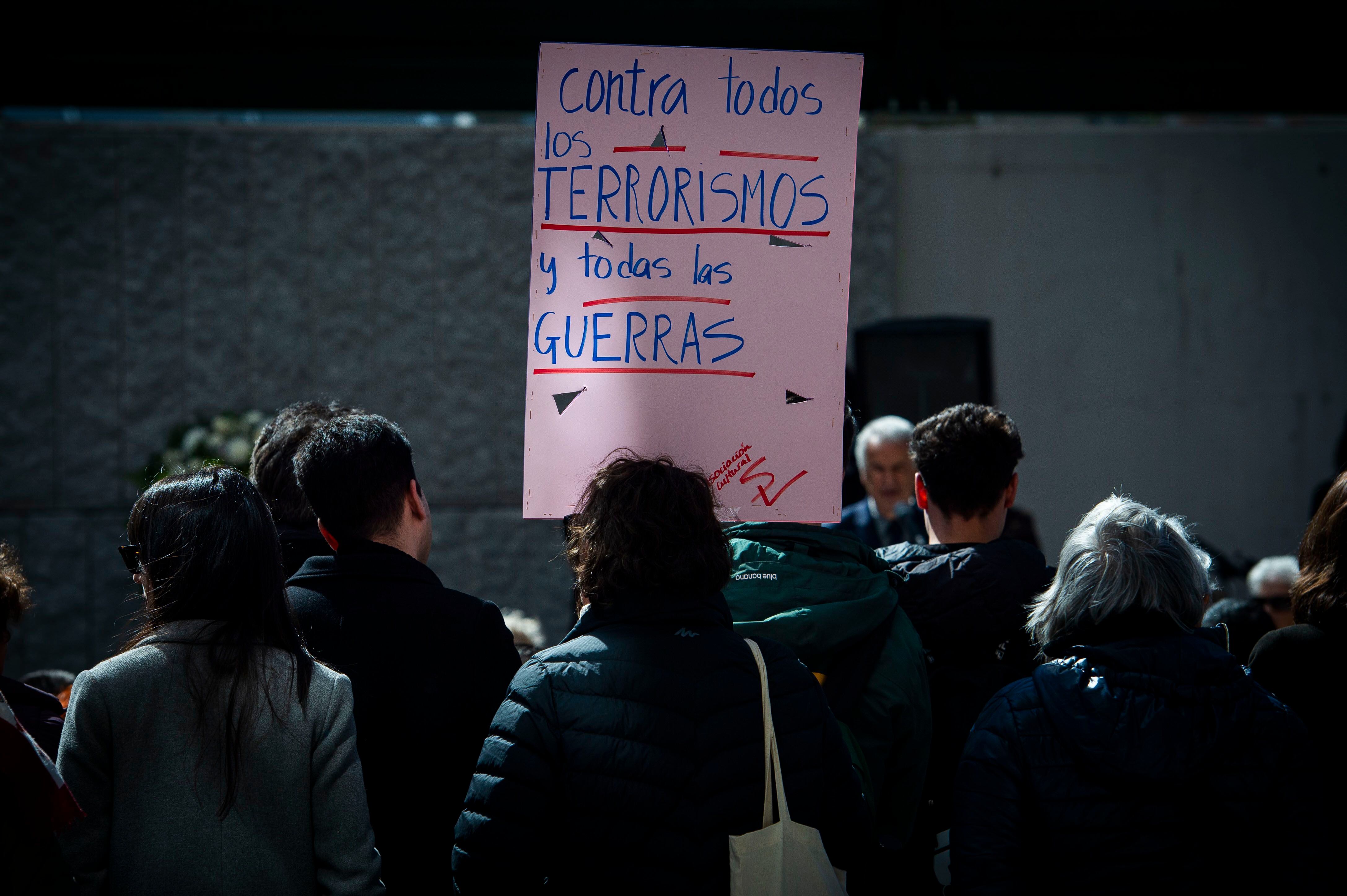 Una mujer levanta una pancarta durante el acto de homenaje celebrado por las víctimas de los atentados del 11-M, este lunes en la calle Téllez.