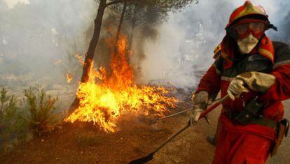 Un bombero intenta apagar las llamas en Torremanzanas (Alicante), donde ayer muri&oacute; un brigadista.