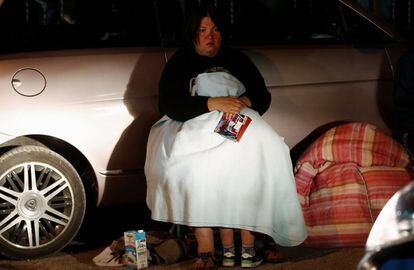 Una mujer se tapa con una manta cerca de un coche donde se prepara para pasar la noche, en Amatrice. 