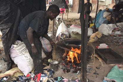 Henry Karisa queima roupas usadas para fritar amendoins no mercado de roupas de segunda mão Kongowea, na cidade queniana de Mombaça.