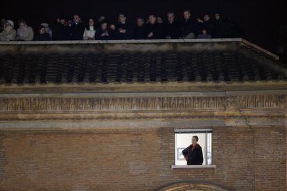 Una mujer espera junto a una ventana el anuncio del nombre del nuevo papa en uno de los balcones de la plaza de San Pedro en el Vaticano.