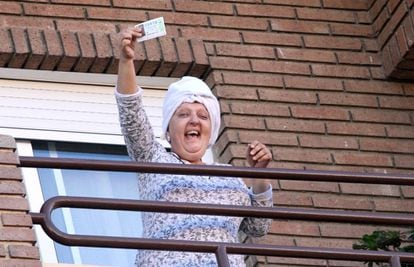 Una mujer muestra desde su balcón el quinto premio, en Valencia, en la zona del puerto.