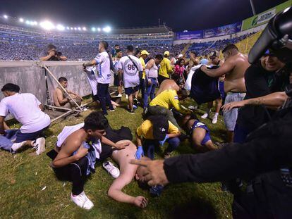 Varios aficionados tratan de ayudar a personas heridas tras la estampida en el Estadio Cuscatlán de El Salvador, donde han muerto al menos 12 personas.