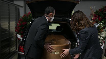 Dos conductores introducen un feretro en el interior de un vehiculo fúnebre en el tanatorio de Sancho de Avila (Barcelona).