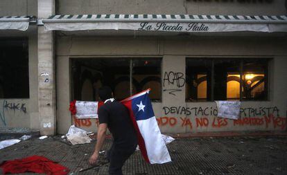 Un manifestante camina frente a un restaurante cerrado en Santiago de Chile.