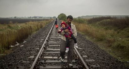 Un padre camina por las vías del tren con su hijo en brazos después de cruzar la frontera entre Serbia y Hungría (Roszke, Hungría, septiembre de 2015).
