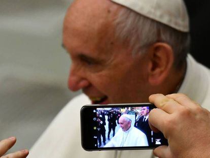 Una persona toma una foto del papa Francisco con un tel&eacute;fono m&oacute;vil.