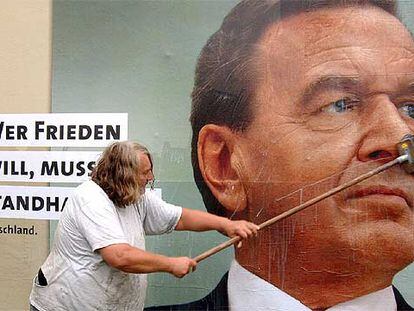 Un hombre pega un cartel electoral del canciller Schröder en Dusseldorf.