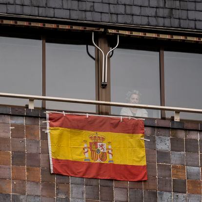 Una vecina de Carabanchel se asoma el pasado viernes a la ventana, en la que ha colocado una bandera de España.