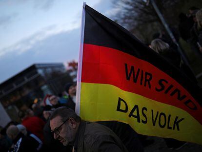 Un simpatizante de AfD lleva una bandera donde se lee "Nosotros somos el pueblo" en una marcha en Erfurt en marzo de 2020.