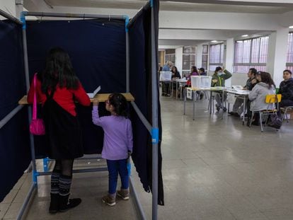 Una mujer junto a su hija dentro de una urna electoral en el Colegio Víctor Jara, La Pintana (Santiago).