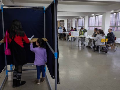 Una mujer junto a su hija dentro de una urna electoral en el Colegio Víctor Jara, La Pintana (Santiago).