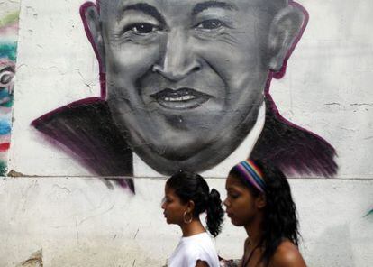 Dos mujeres caminan frente a un grafiti con la imagen del presidente venezolano Hugo Ch&aacute;vez en el centro de Caracas (Venezuela). 
