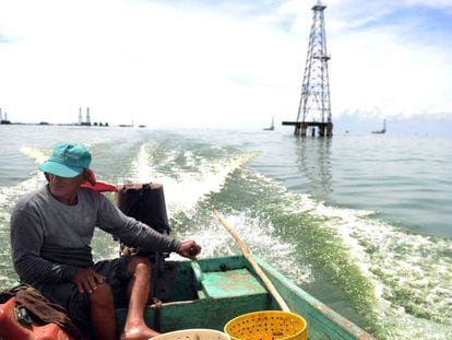 Un pescador navega frente a una torre petrolera en el lago Maracaibo.