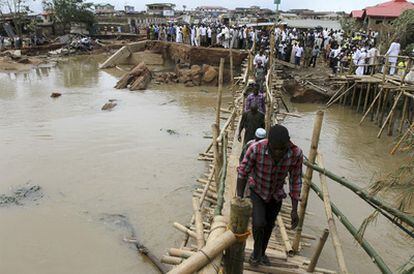 Habitantes de la ciudad de Ibadan cruzan por un puente de juncos después de las crecidas.