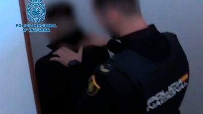 Uno de los detenidos, escoltado por un policía, en la operación por estafar miles de euros a cientos de personas por internet, en una imagen de la Policía Nacional.