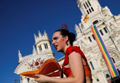 Un participante de la manifestación frente al Palacio de Cibeles, adornado con la bandera del Orgullo Gay.