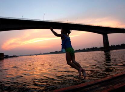 Una niña tailandesa salta a las aguas del Mekong, junto al puente que une Tailandia y Laos en Nong Khai