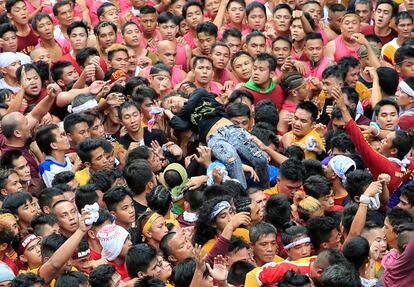 Una joven es elevada tras sufrir un desmayo tras intentar alcanzar la carroza del Cristo Negro por las calles de Manila (Filipinas).