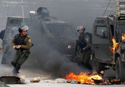 Dos guardias fronterizos israelíes huyen de un vehículo militar en llamas durante los enfrentamientos con manifestantes palestinos en las afueras de Ramallah, en la ocupada Cisjordania.