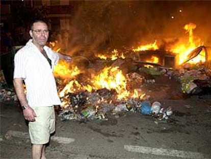 Un vecino de Málaga señala los contenderos incendiados en protesta por la huelga de limpieza.