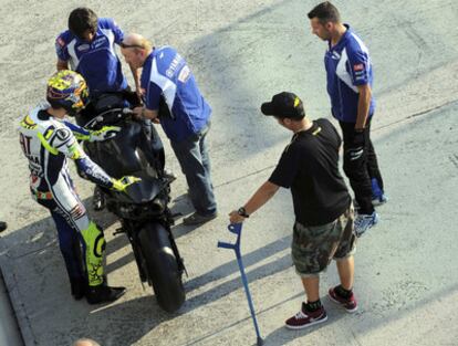 Valentino Rossi intenta subir a la moto mientras un miembro de su equipo le sujeta la muleta en Misano.