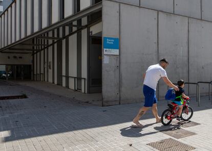 Un padre y su hijo pasean frente a una escuela cerrada en el barrio del Poble Nou.