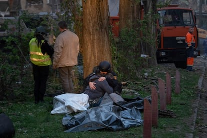 Una psicoterapeuta de rescate abraza a una mujer que perdió a un ser querido, frente a los cuerpos de las víctimas, tras un ataque ruso en un barrio residencial de Kiev, este jueves.