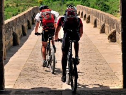Dos ciclistas en el puente rom&aacute;nico de Puente la Reina, en el Camino de Santiago a su paso por Navarra. 