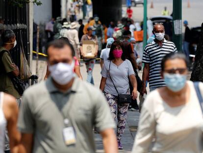 Varias personas caminan por Caracas portando máscaras.