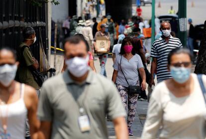 Varias personas caminan por Caracas portando máscaras.