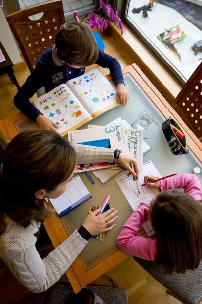 Una madre ayuda a sus hijos a realizar los deberes escolares en casa